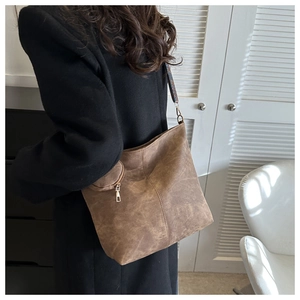Détail d'un sac cabas en daim marron avec large bandoulière à motifs et poche zippée latérale