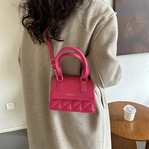 Retro hot pink mini crossbody bag with geometric quilting and golden logo on strap