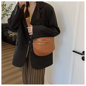 Détail du sac demi-lune en cuir marron avec triple fermeture éclair dorée et bandoulière