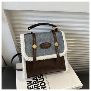 Detail of faux shearling trim on retro leather backpack with metal buckle on white book
