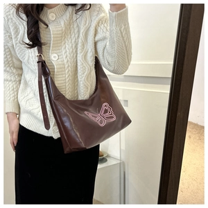 Detail of a brown shoulder bag with pink butterfly embroidery and adjustable leather strap