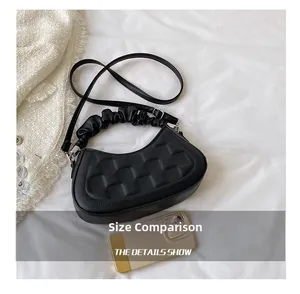 Close-up of black quilted small square bag with scrunchie handle and phone for size reference