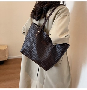 Close-up of brown woven leather tote bag with fashion label and slim shoulder strap