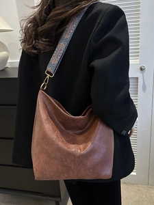 Gros plan sur un sac seau en cuir PU marron avec large bandoulière style bohème