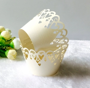 Detail of laser-cut heart pattern on cream cupcake wrapper over white plush surface