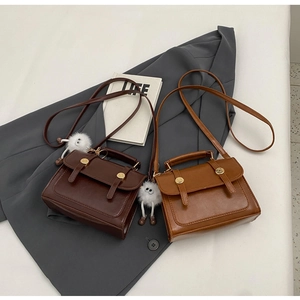 Retro PU leather handbags in brown and tan with plush monster charms on grey blazer