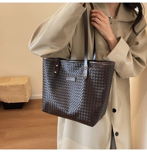 Detail of dark brown woven texture on large tote bag with metallic fashion plaque