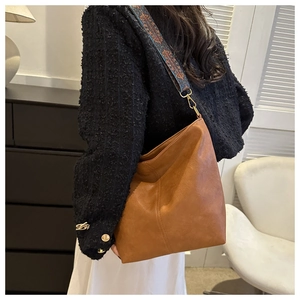 Détail d'un sac seau en cuir PU marron souple avec une bandoulière ethnique colorée