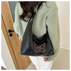 Detail of black faux leather tote featuring a large pink embroidered butterfly pattern