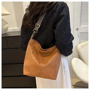 Détail d'un sac cabas marron avec bandoulière tissée colorée et crochet en bronze poli