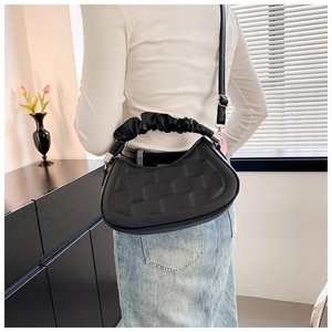 Modern black pleated shoulder bag with unique cloud handle shown in stylish home interior