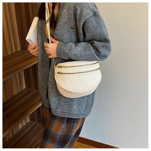 Détail de sac banane blanc grainé avec double fermeture éclair dorée et bandoulière