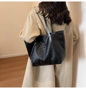 Detail showing high-capacity black woven tote bag texture with fashion label and shoulder strap