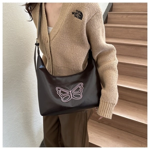 Detail of a black leather crescent shoulder bag featuring pink butterfly embroidery