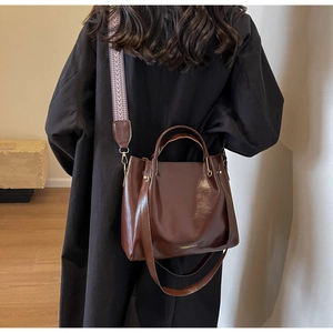 Dettaglio della borsa a secchiello marrone vintage con tracolla ampia a motivi geometrici