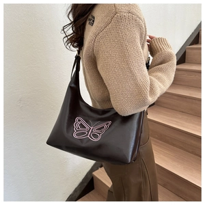 Close-up of the delicate pink butterfly embroidery on a dark brown faux leather hobo bag