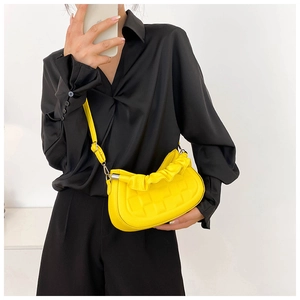 Macro detail of the bright yellow pleated handbag with woven texture on a black shirt
