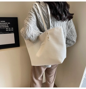 Detail of white woven leather tote bag featuring gold rivets and textured pattern