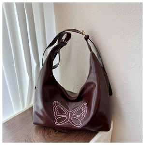 Detail of burgundy tote bag showing embroidery butterfly and adjustable shoulder strap