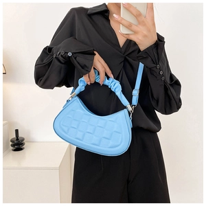 Detail of light blue pleated handbag featuring embossed checkered texture and ruched handle