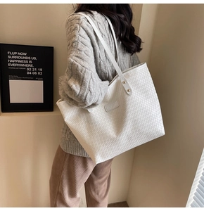 Detail of woven lattice texture on white tote bag with gold rivets and leather label
