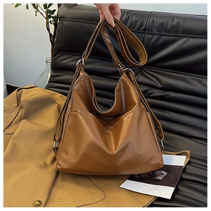 Détail d'un grand sac fourre-tout marron sur un canapé noir avec éclairage chaleureux