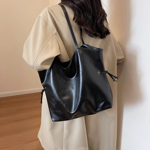 Grand sac cabas chic en similicuir noir avec détails de cordon sur un manteau beige