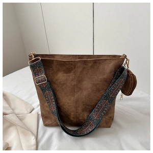 Détail d'un sac cabas en daim marron avec une large bandoulière à motif ethnique