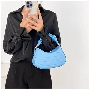 Close-up of sky blue handbag featuring checkerboard texture and pleated cloud handle