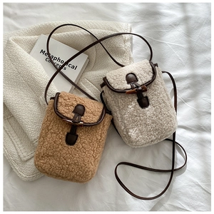 Détail de sacs bandoulière en polaire Sherpa avec boucles en corne sur literie blanche