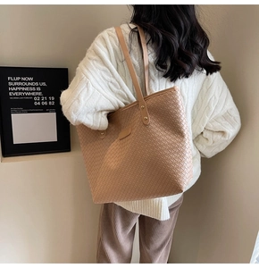 Close-up of khaki woven tote bag with premium leather handles and gold metal rivets