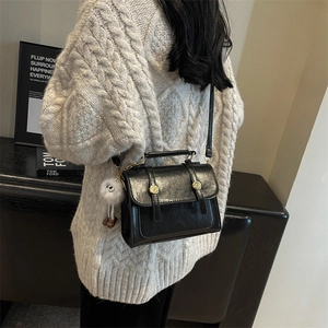 Minimalist black PU leather square handbag with plush charm and long strap shown on model