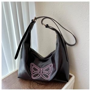 Close-up of black PU tote bag with pink butterfly embroidery and golden hardware