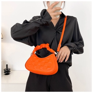 Detail of bright orange pleated handle handbag with woven texture and adjustable strap