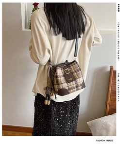 Plaid wool bucket bag detail featuring a cute rabbit charm and leather shoulder strap