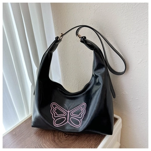 Close-up of pink butterfly embroidery and gold buckle on a black PU leather hobo bag