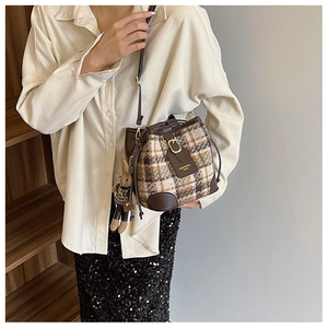 Detail of plaid tweed bucket bag with leather trim and cute rabbit doll charm