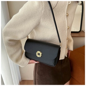 Vue détaillée du sac en cuir noir mat avec une boucle dorée en forme de nœud rond