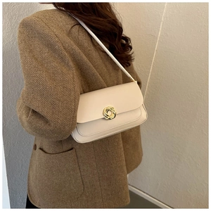 Détail d'un sac sous le bras en cuir blanc crème avec boucle dorée et coutures soignées