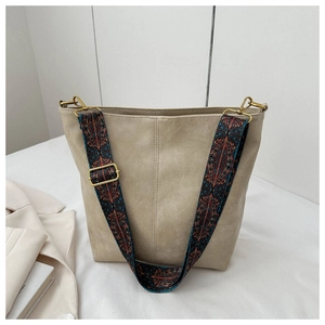 Détail du sac seau beige avec une bandoulière tissée ethnique colorée et des attaches en métal