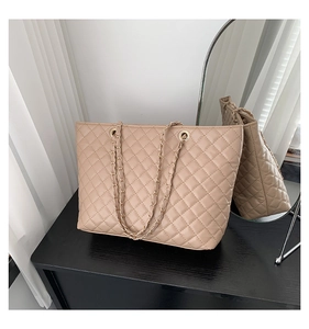 Dettaglio della borsa tote trapuntata beige con tracolla a catena dorata e cuciture