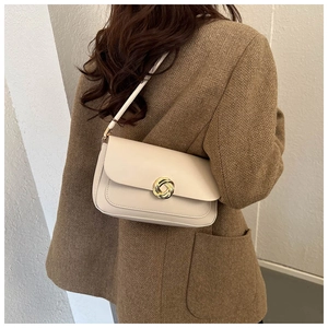 Détail du sac à bandoulière crème avec boucle dorée sur mannequin en veste de tweed