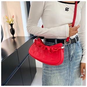 Detail of red crescent bag with pleated edges and premium lychee texture leather finish