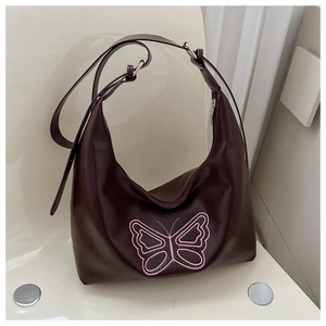 Detail of dark brown hobo bag featuring intricate pink butterfly embroidery and vegan leather