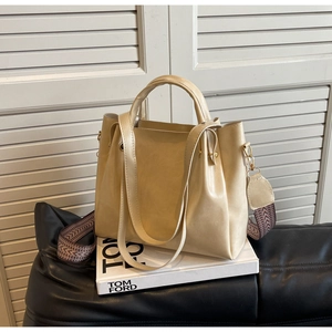 Dettaglio della borsa a secchiello beige con tracolla intrecciata e ganci in metallo