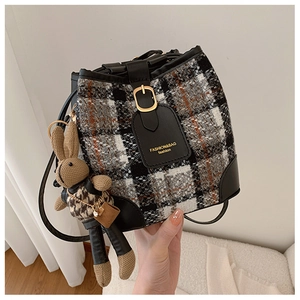 Detail view of plaid tweed bucket bag with black leather trim and cute rabbit charm