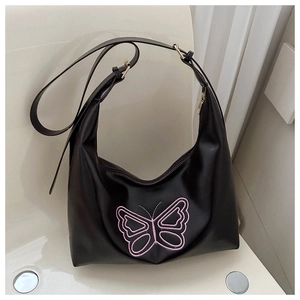 Detailed view of black hobo bag featuring pink embroidered butterfly and gold buckle