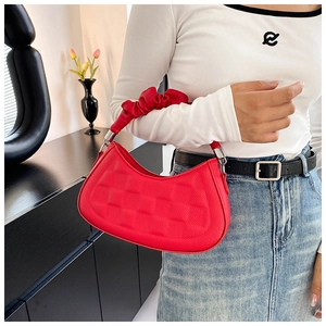 Detail of red crescent handbag with square embossed pattern and ruched handle