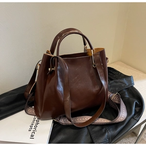 Dettaglio borsa a secchiello marrone vintage con tracolla etnica e chiusura dorata