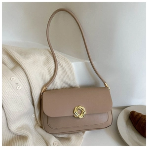 Détail d'un sac sous le bras taupe minimaliste avec un fermoir doré élégant sur maille